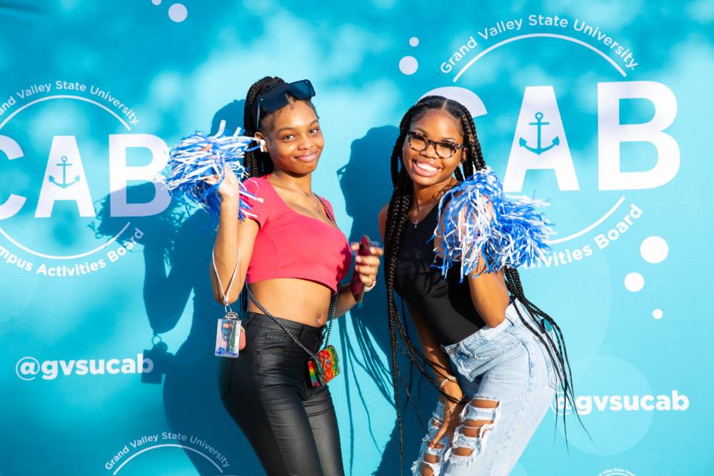 two students posing  and smiling in front of CAB backdrop at Laker Kickoff photo booth